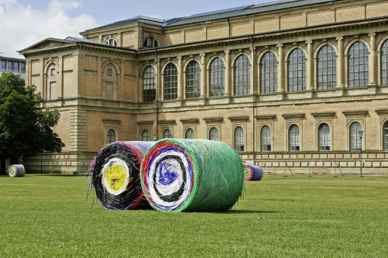 Auf der Wiese vor der Alten Pinakothek liegen zwei riesige bunte Ballen aus Strohhalmen.