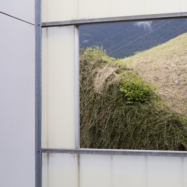 Image section of the view of a billboard on a prefab building with the motif of a dried-up meadow and bushes in a hilly landscape