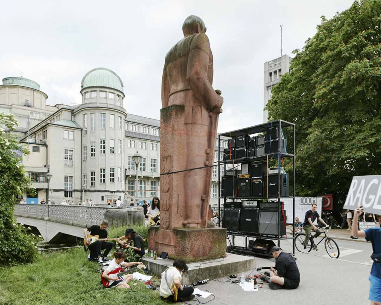 Musizierende junge Menschen rund um das Bismarck-Denkmal. Im Hintergrund ist das Deutsche Museum zu sehen.