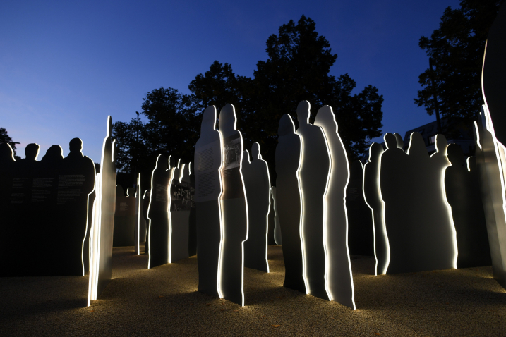 View of the blue-black evening sky, in the foreground the silhouettes of the figures are illuminated