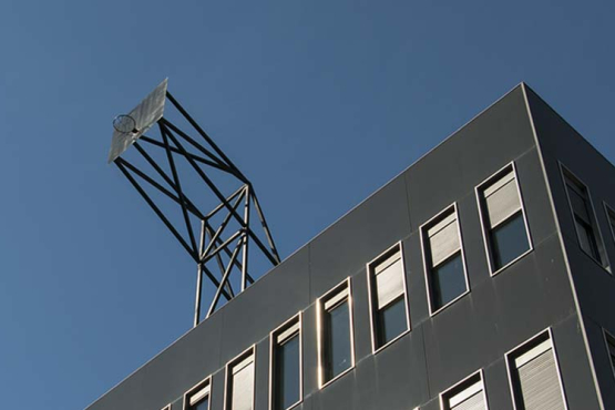 Eine Basketballkorbwand ist auf dem Dach eines hohen Hauses montiert und ragt in den blauen Sommerhimmel.