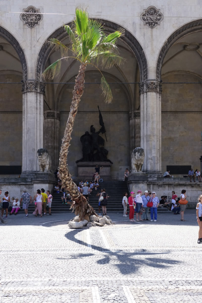 On the Odeonsplatz, directly in front of the Feldherrnhalle, a 12 meter high palm tree appears to be growing straight out of the pavement.