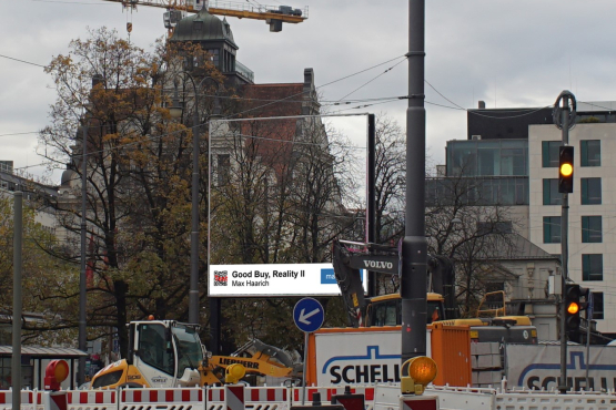 Blick auf das Billboard vor Bäumen und einer historischen Häuserfassade. Das Motiv auf dem Billboard ergänzt exakt den Bildausschnitt, welcher durch das Billboard verdeckt ist, so dass es scheint, man sehe durch dieses hindurch