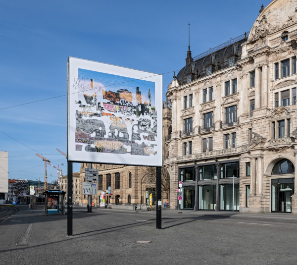 Diagonale Ansicht des Billboards. Über einer farbigen Collage aus Bild, Wort und Zeichen erscheint kaum lesbar der Satz "Whose Utopia we shall return to".