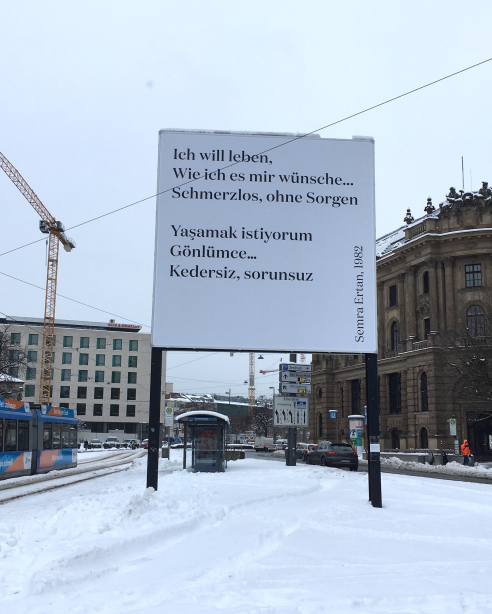 Frontaler Blick auf die Rückseite des Billboards. In schwarzer Schrift auf weißem Grund steht ein Ausschnitt aus dem Gedicht “Ich will leben“ der Poetin Semra Ertan von 1982 auf deutsch und türkisch.
