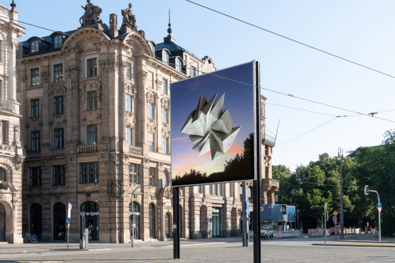 Diagonal view of the billboard side facing towards the city center. The motif shows an abstract stone formation floating above trees in front of a sunrise.