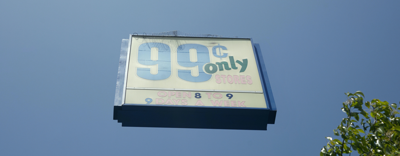 Das Motiv zeigt ein Werbebillboard mit der Aufschrift "99 Cents only stores" vor blauem Himmel, das ohne Stützstrukturen frei über der Erde zu schweben scheint.