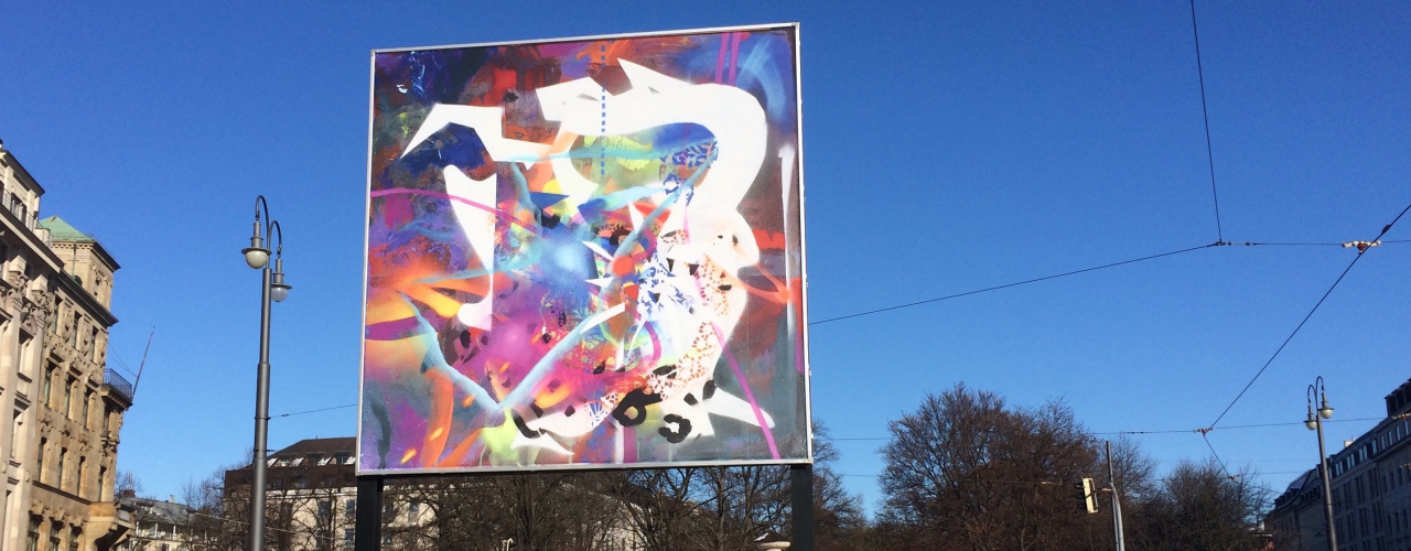 Frontale Ansicht des Billboards am Lenbachplatz. Das Motiv zeigt eine abstrakte Komposition aus leuchtend bunten, sich überlagernden Farben, Formen und Strukturen.