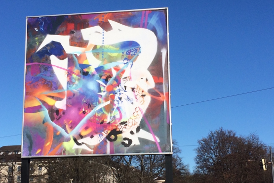 Frontal view of the billboard on Lenbachplatz. The motif shows an abstract composition of brightly colored, overlapping colors, shapes and structures.