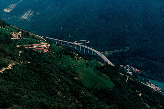 Photo collage of a wooded landscape with an elevated highway bridge describing a loop.