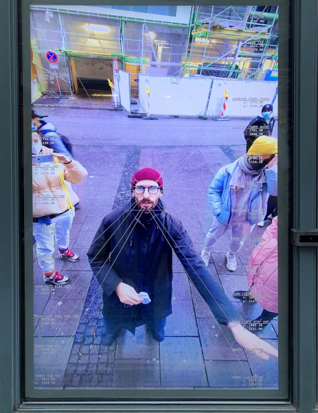 A man wearing a red cap is reflected in a shop window. Starting from his face, white lines appear on the glass, leading to different coordinates.