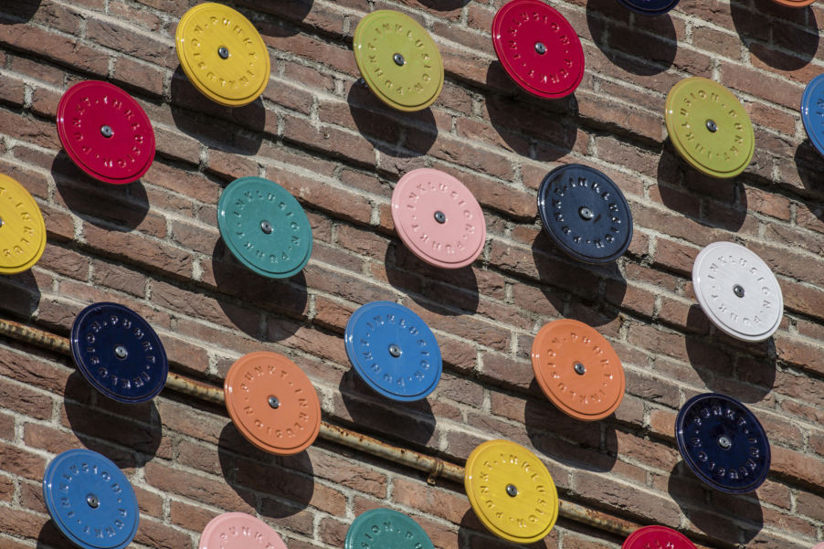 Close-up of several differently coloured glazed ceramic discs mounted on a brick wall.
