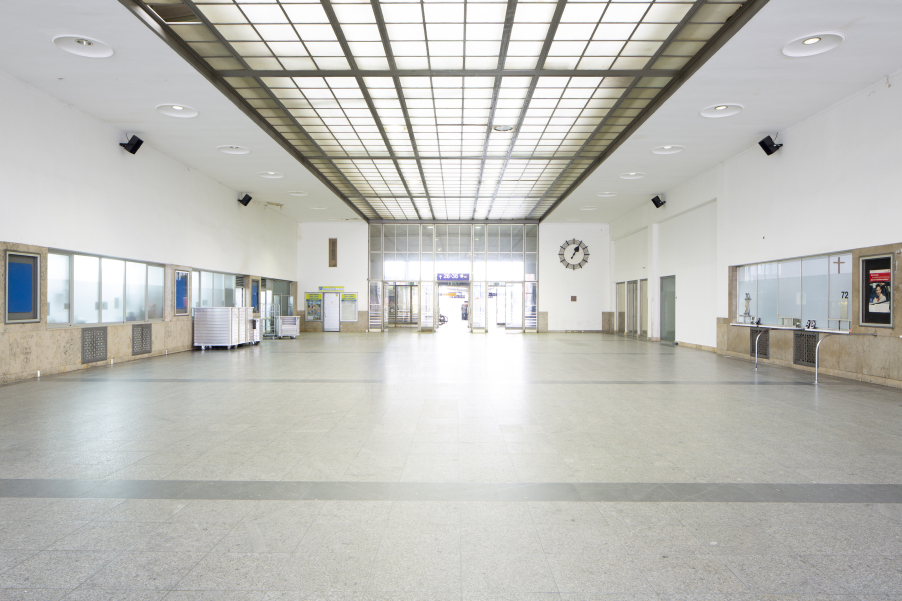 View of the deserted station concourse of the Starnberger Flügelbahnhof Munich with closed ticket counters. Black loudspeakers are mounted on the walls.