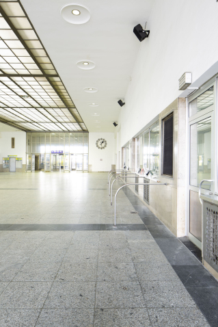 View of the deserted station concourse of the Starnberger Flügelbahnhof Munich with closed ticket counters. Black loudspeakers are mounted on the walls.