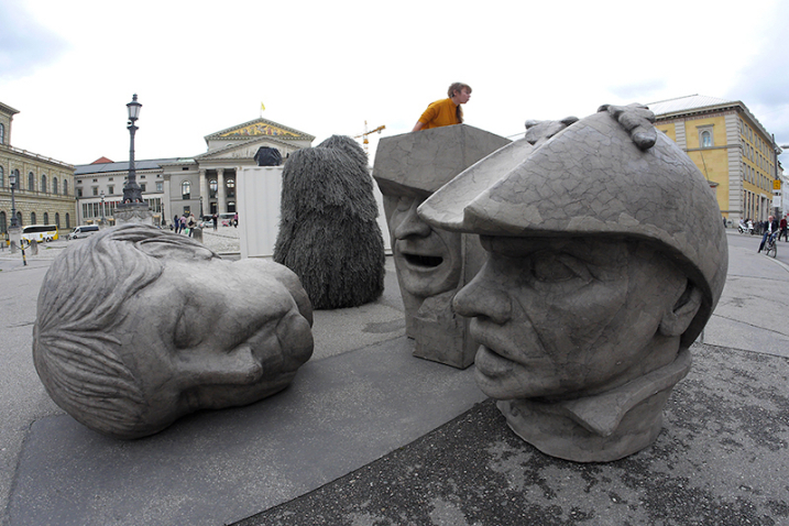 Three grey sculptures in the form of oversized heads can be seen on Max-Joseph-Platz. The heads bear the likenesses of Angela Merkel, ECB President Mario Draghi and Dutty Boukman, the leader of the first slave rebellion in Haiti in 1791.