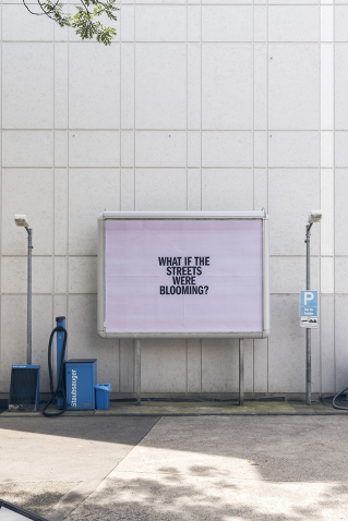 View of a petrol station with an advertising billboard. The question "WHAT IF THE STREETS WERE BLOOMING" is written on the purple background of the billboard.