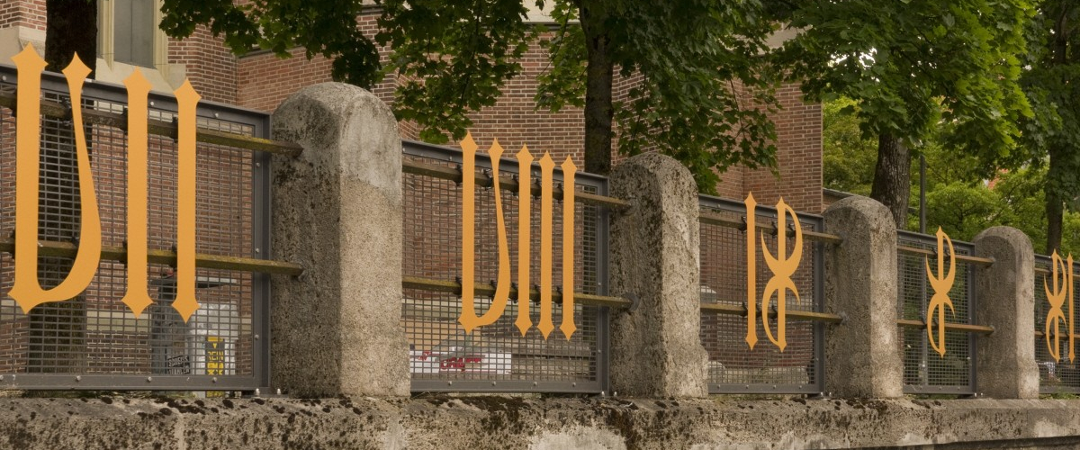 Several golden metal numerals are attached to the fence in front of the Heilig-Kreuz-church on Giesinger Berg hill.