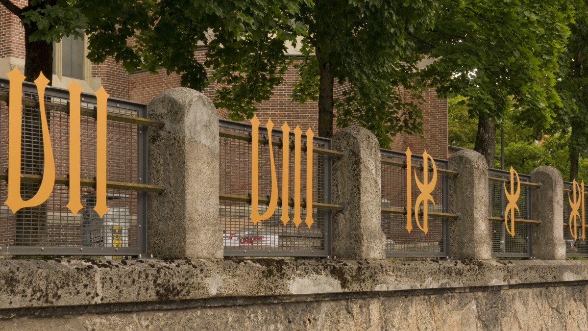 Several golden metal numerals are attached to the fence in front of the Heilig-Kreuz-church on Giesinger Berg hill.