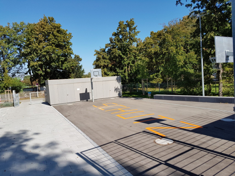 Eingezäunter Basketballplatz mit dem aufgeklebtem Schriftzug "Schutz" in gelben Lettern.