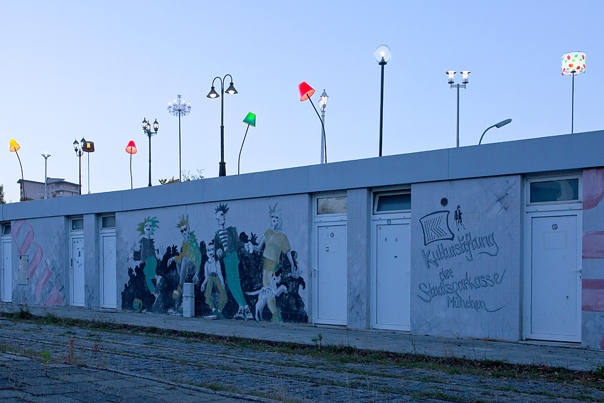 Various colourful lights mounted on the tram shelter at Ratzingerplatz in Munich at dusk.