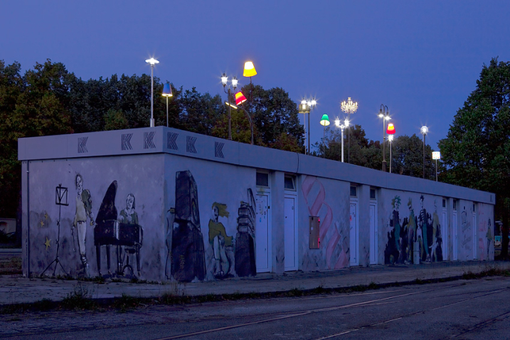 Various colourful glowing lights mounted on the tram shelter at Ratzingerplatz in Munich at dusk.