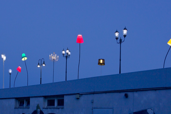 Various colourful glowing lights mounted on the tram shelter at Ratzingerplatz in Munich at dusk.