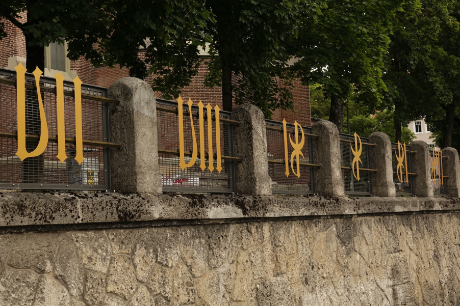 Several golden metal numerals are attached to the fence in front of the Heilig-Kreuz-church on Giesinger Berg hill.