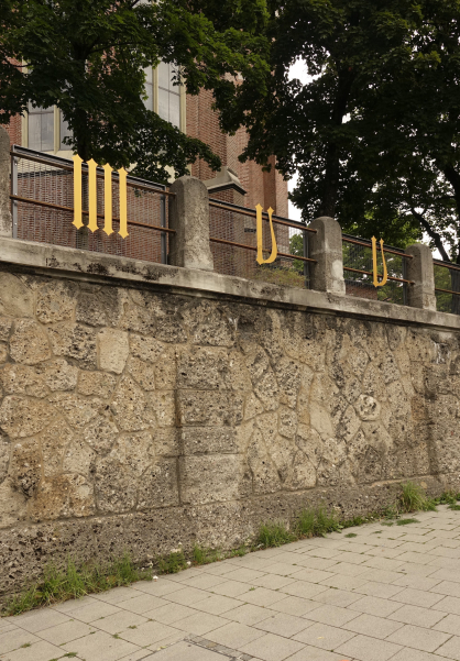 Several golden metal numerals are attached to the fence in front of the Heilig-Kreuz-church on Giesinger Berg hill.