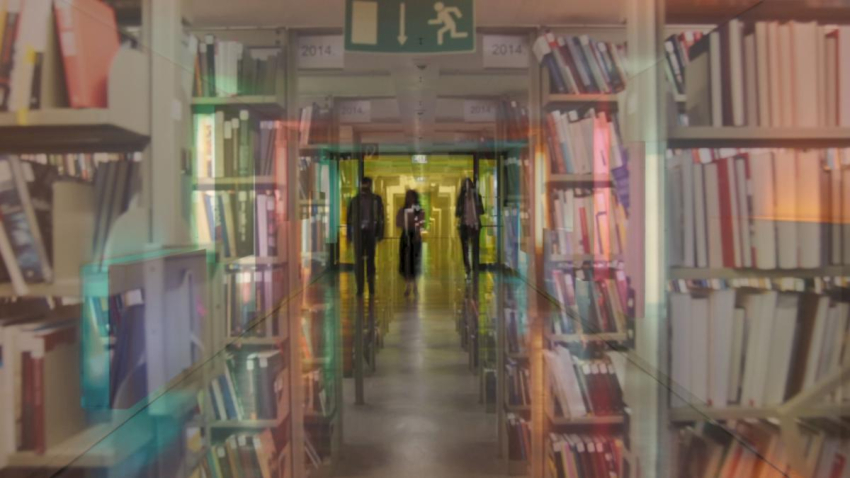 Screenshot of the video "Hors Champ". Mirrored blurred photograph of a library aisle with several rows of shelves on both sides and three people who can be recognised out of focus at the end of the aisle.