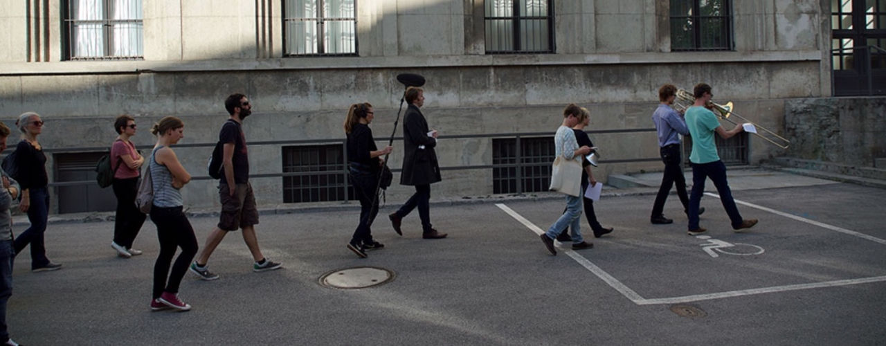 A group of people follow two musicians with wind instruments leading this march.