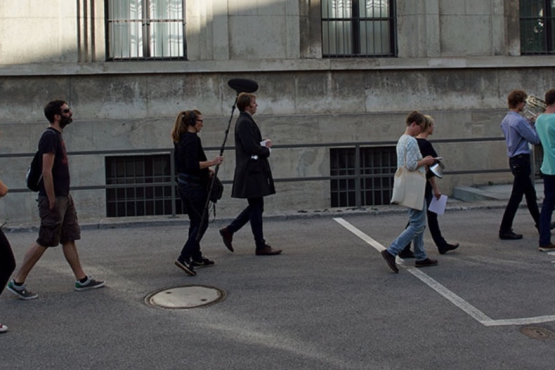 A group of people follow two musicians with wind instruments leading this march.