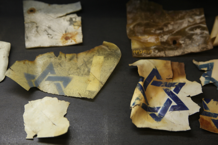 Fotografie von mehreren abgerissenen Pergamentstücken mit blauem Davidstern.