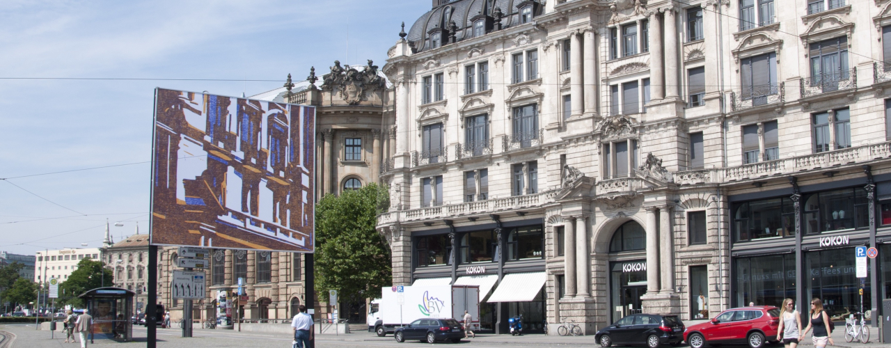 View of the billboard on Lenbachplatz looking towards the city with the motif "hide and seek" by Angela Stauber. The motif is a mirror image of the building to the right of the billboard. The architectural forms of the historic façade are simplified using the woodcut technique and abstracted into a block-like aesthetic of coloured surfaces in white, yellow and blue.