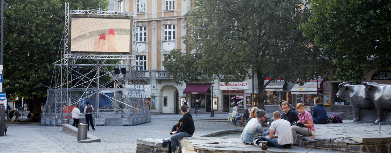 A metal scaffolding with a video screen mounted on it shows Nevin Aladağ's video work "Top View" at Munich's Rindermarkt.