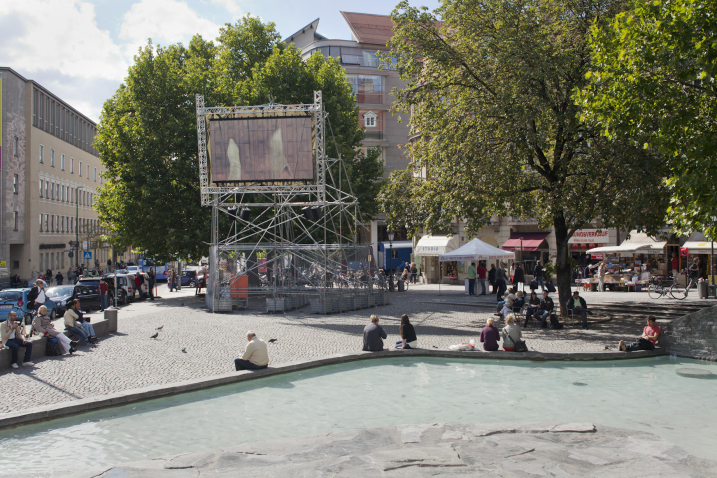 A metal scaffolding with a video screen mounted on it shows Nevin Aladağ's video work "Top View" at Munich's Rindermarkt.