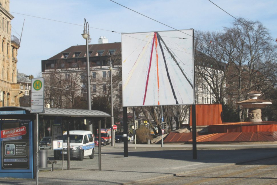 Slightly diagonal view of the billboard on Lenbachplatz. The motif shows an abstract composition with coloured lines on a white background.