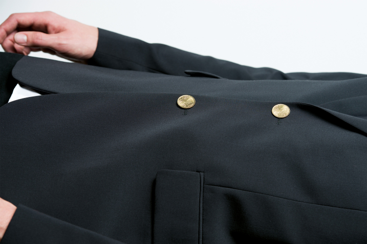 Fotografie einer Person in schwarzem Anzug, dessen Knöpfe 20-Eurocent-Münze sind. Zu sehen ist nur der Oberkörper der Person und das Bild ist um 90-Grad gedreht.