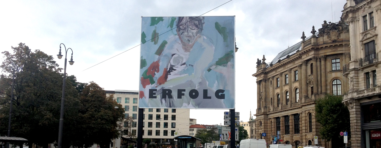 Frontal view of the billboard at Lenbachplatz photographed towards the city centre. The billboard features a work by the artist Stephan Dillemuth. The motif shows an abstract portrait of a naked man against a blue-green background. The word "Erfolg" (success) is written in bold black capital letters in the lower third of the image.