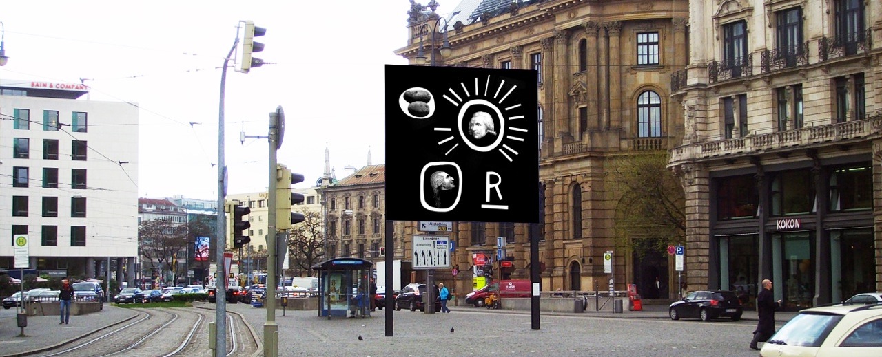 Seitliche Ansicht des Billboards am Lenbachplatz mit Blick Richtung Innenstadt. Auf dem Billboard zu sehen ist eine Arbeit des Künstlers Martin Fengel. Das Motiv zeigt auf schwarzem Hintergrund vier Objekte. Ein weißes unterstrichenes "R" in Großbuchstaben. Ein weißer Kreis mit einem grauen Bild von zwei Kartoffeln. Ein weißer Kreis mit seitlich ausgehenden Strahlen, in dessen Mitte ein Schwarz-Weiß-Porträt des Grafen Rumfords sitzt. Ein zweiter Kringel mit einem Schwarz-Weiß-Porträt eines Mannes im Profil, eventuell ebenfalls Graf Rumford.
