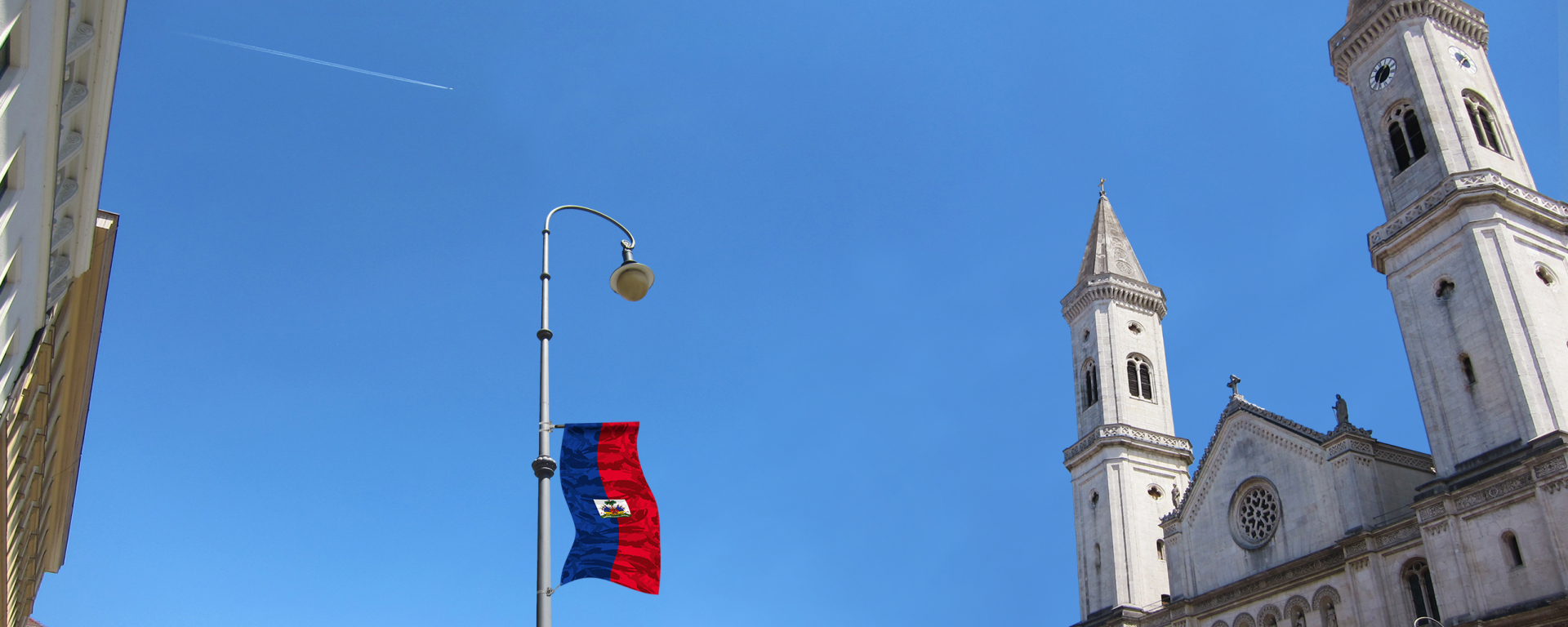View of a street lamp on Ludwigstraße, photographed from below. As part of an art installation by artist Silke Witzsch, the national flag of Haiti is attached to the street lamp at half height. The flag has been artistically distorted by placing a camouflage pattern over the national flag.