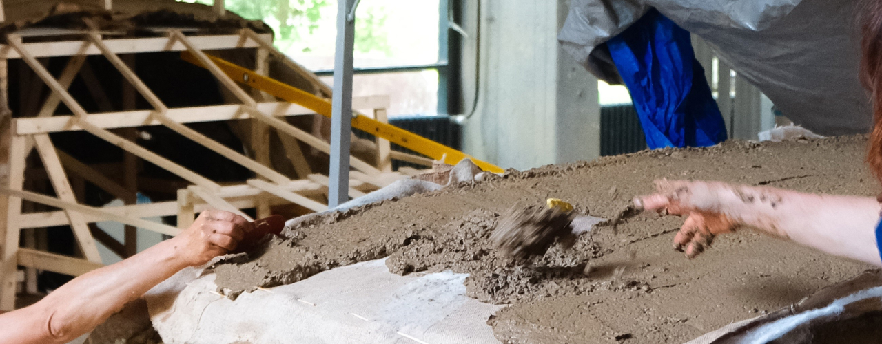 Production of the compostable SUV, the clay-like mass is applied to a wooden frame covered with tarpaulins.