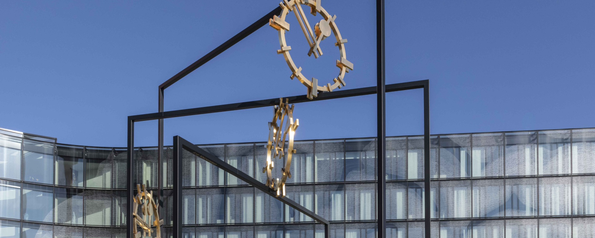 Eine große Skulptur aus Stahl mit drei goldenen Ziffernblättern
