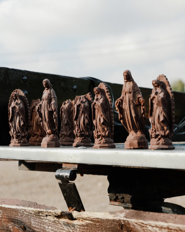 Mehrere kleine Heiligenfiguren aus braunem Material stehen in einer Reihe.