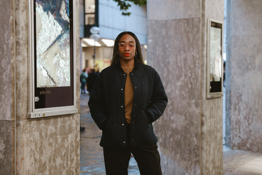 Person steht zwischen steinernen Pfeilern mit Bildschirmen im öffentlichen Raum.