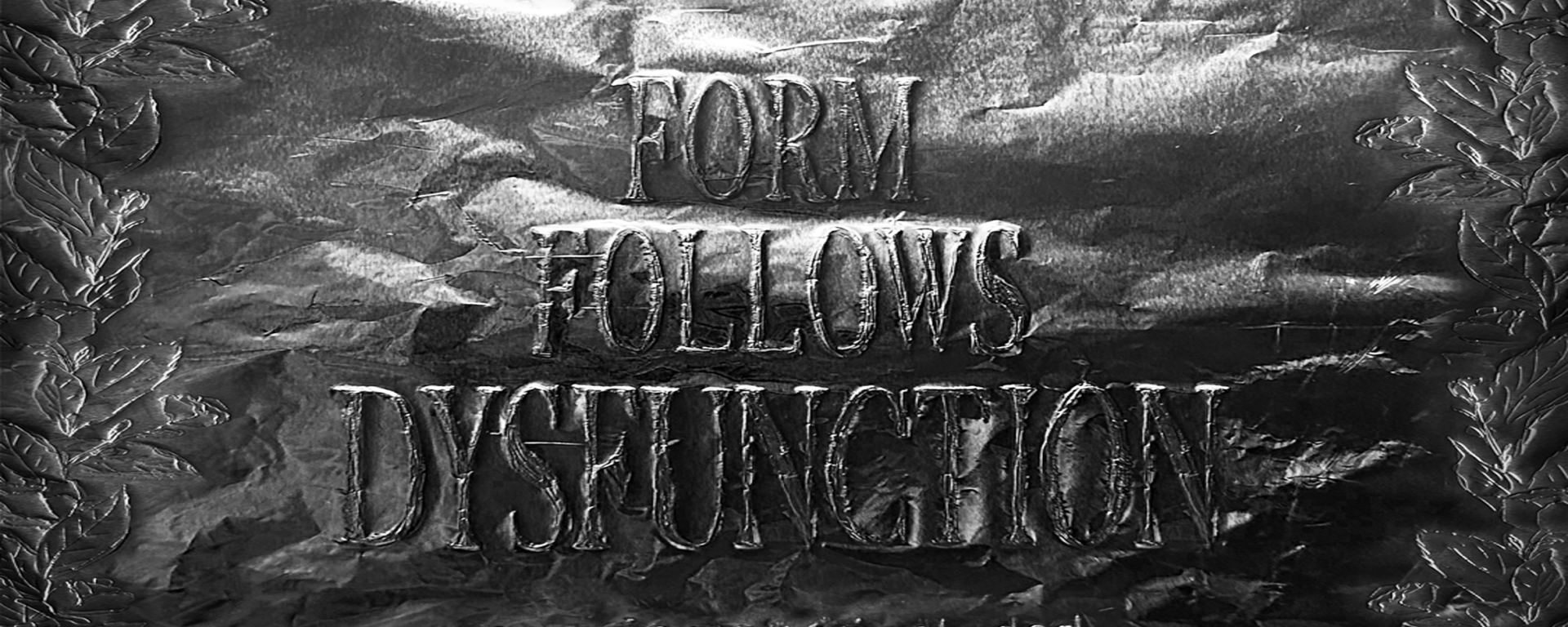 Silberne, zerknitterte Oberfläche mit geprägter Schrift: ‚Form Follows Dysfunction‘