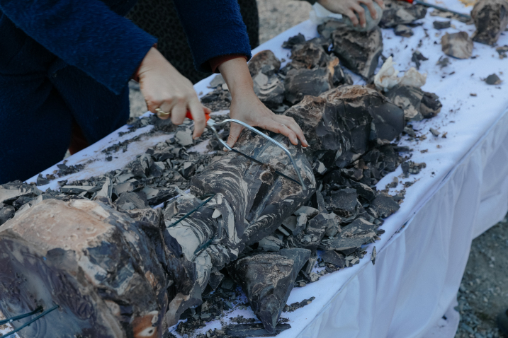 Person sägt eine zerbrochene Skulptur auf einem mit weißen Tüchern bedeckten Tisch.