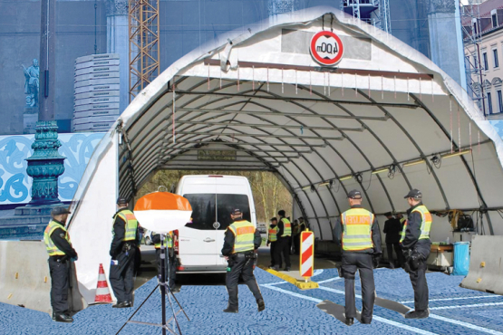 Eine temporäre Kontrollstelle mit Zeltdach und mehreren Sicherheitskräften steht auf einem Platz vor einem historischen Gebäude mit Gerüst und Kran.