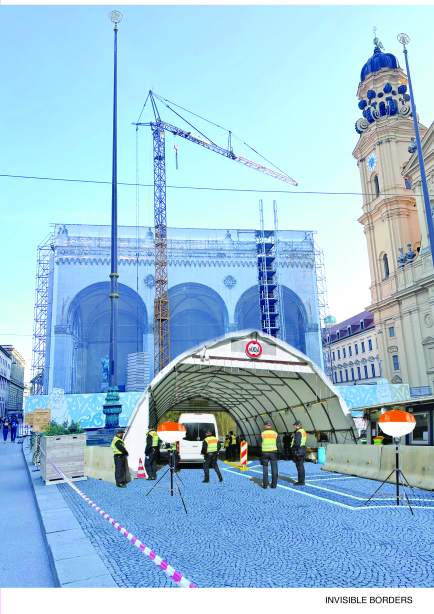 Eine temporäre Kontrollstelle mit Zeltdach und mehreren Sicherheitskräften steht auf einem Platz vor einem historischen Gebäude mit Gerüst und Kran.