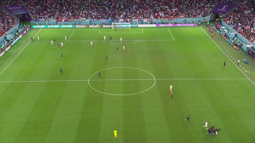 Blick auf ein Fussballspiel von oben in einem gut besetzten Fussballstadion, rechts unten ist eine schwarz gekleidete Personengruppe zu sehen, die vom Feld zu laufen scheint.