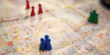 Colorful game pieces (blue, red, green) are placed on a city map.